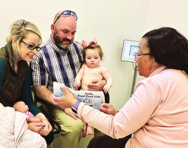 Dr. Ellis reading to an infant with parents