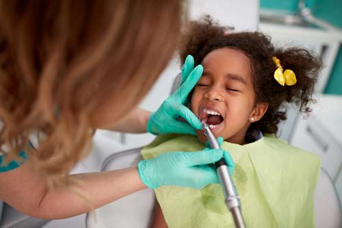 Little girl getting her teeth inspected at the dentist